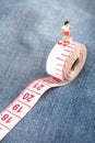 Miniature puppet women running and exercising on a tape measure