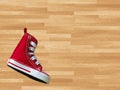 Miniature red baskeball shoe on wooden floor as background