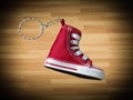 Miniature red baskeball shoe on wooden floor as background