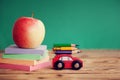 Miniature Red Car Carrying a colorful pencils and red apple and stack papers on wooden table. Back to school concept Royalty Free Stock Photo