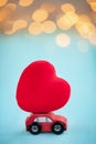 Miniature red car carrying a red heart on shine bokeh background Royalty Free Stock Photo