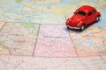 Miniature red car driving on a map of the pairie provinces, canada