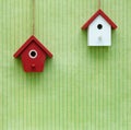 Miniature red and white birdhouses on the green background