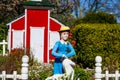 A miniature red and white house with a clay statue of a woman in a blue dress with a white picket fence