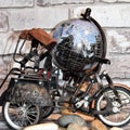 Miniature rickshaw with small rocks, brick wall and globe