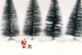 Miniature Santa Claus and artificial Christmas trees with snow background.