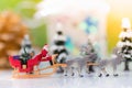 Miniature Santa Claus drive a wagon with a reindeer during the snowfall. Using as concept in Christmas day