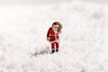 Miniature Santa Claus walking through snow