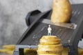 Miniature scale model chef, standing on stacked potato, with kitchen cutter mandolin