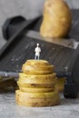 Miniature scale model chef, standing on stacked potato, with kitchen cutter mandolin