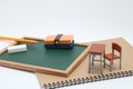 Miniature school desk, chalkboard and notebook on white background.