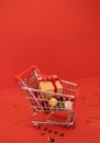 Miniature shopping cart with craftpaper gift on a red background