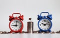 Miniature shopping cart on a pile of coins between two alarm clocks. Royalty Free Stock Photo