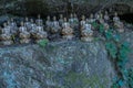 Miniature sitting Buddhas on ledge of boulder