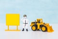 Miniature soldier in hazmat suite with blank sign and front loader truck over blurred blue background
