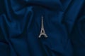 A miniature statuette of the Eiffel Tower on a dark blue cloth background. Souvenir from Paris. Trend minimalism. Royalty Free Stock Photo