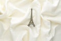 Miniature statuette of the eiffel tower on a white silk background. Trend minimalism Souvenir from Paris. Royalty Free Stock Photo