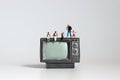 The miniature television and miniatures of mothers and fathers with babies.