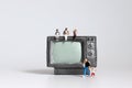 The miniature television and miniatures of mothers and fathers with babies.