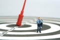 A businessman standing above dartboard with red arrow, thinking strategy effectiveness Royalty Free Stock Photo