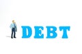 A stress and depressed businessman standing beside DEBT wooden word letter