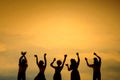 Miniature tiny people toys photography. Silhouette upper body group of teens raised hand or hands up celebration on sunset orange