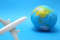 Miniature toy airplane and globe on blue background. Royalty Free Stock Photo