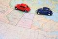 Miniature toy cars driving in tandem on a map of canada