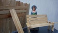 Miniature toy doll women in dress with hat and handicrafts bench chair