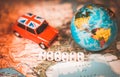 Miniature Toy vintage car,a world map balloon and Travel word on a map.Travel and transport concept. Royalty Free Stock Photo