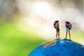 Miniature traveler and hiker backpack standing on the globe for the tourist and adventure around the world for vacations trip.