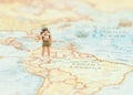 Miniature traveler man with backpack standing on wold map for travel around the world.