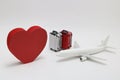 Miniature two suitcases, toy airplane, and a red heart on white background. Royalty Free Stock Photo