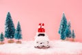 Miniature white car toy delivering gift box and christmas tree on pink background. Christmas greeting card concept Royalty Free Stock Photo