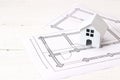 Miniature white toy house with house plan drawing on white woode