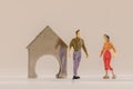 Miniature woman and man figure standing next to house made of coin holder with no coins. Shallow depth of field background. Family Royalty Free Stock Photo
