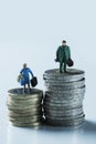 Miniature woman and man on piles of euro coins