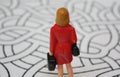 Miniature woman in red coat from behind in the maze. Lost or confused lady decides, which way to go Royalty Free Stock Photo