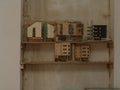 Miniature wooden buildings on display on a wooden shelf against a wall