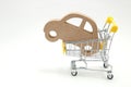 Miniature wooden car and shopping cart on white background. Concept of buying new car. Royalty Free Stock Photo