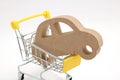 Miniature wooden car and shopping cart on white background. Concept of buying new car. Royalty Free Stock Photo