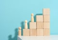 Miniature wooden figurines on wooden block steps, concept of career growth, goal achievement. Personal growth, head of corporation