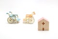 Miniature wooden hospital and wheelchairs on white background.