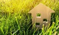 Miniature wooden house on green grass. Real estate concept. Modern housing. Eco-friendly and energy efficient house. Buying a home