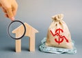 Miniature wooden house and a money bag with a down arrow. The concept of low cost real estate. Lower mortgage interest rates. Royalty Free Stock Photo
