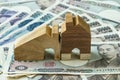 miniature wooden house on pile of japanese yen banknotes as financial or real estate mortgage concept