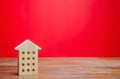 Miniature wooden house on a red background. Sweet Home concept. Buying and selling real estate. Affordable housing for young