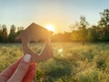 Miniature wooden house in the shape of a heart in the hands of a girl outdoors. Real estate concept. Eco-friendly home. Buying a Royalty Free Stock Photo