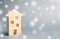 Miniature wooden house and snowflakes. Demand for real estate in the winter. Christmas discounts and sale. Rental of housing.