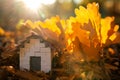 Miniature wooden house with yellow leaves on a sunny autumn day. Real estate and affordable housing concept. Mortgage, loan and